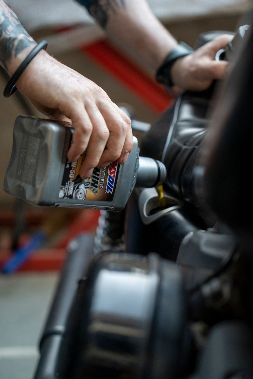 close up of a man pouring oil into a motorcycle